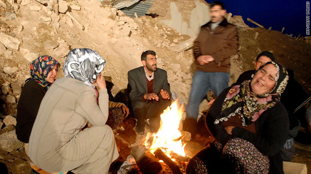 Quake survivors gather around a fire near the ruins of their homes.