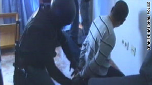 One of the suspects is cuffed by Spanish police.