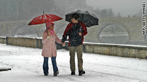 A couple strolling on the embankment of the river Vardar, enjoying the snowfall that turned the city white.