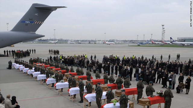 Soldiers and family members stand by the coffins of 25 victims of the April plane crash that killed Poland's president.