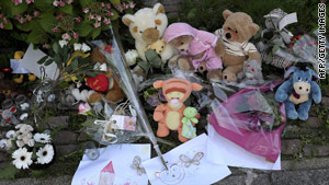 Toys and flowers lie in tribute outside a house where the bodies of three babies were found.