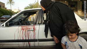 A woman peeks inside a blood-stained car in Baghdad, Iraq, after the shootout in 2007.