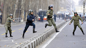 Iranian riot policemen pursue opposition supporters during protests in Tehran on December 27, 2009.
