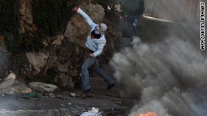 A Palestinian youth hurls stones at Israeli soldiers at the West Bank refugee camp of Qalandia on Thursday.