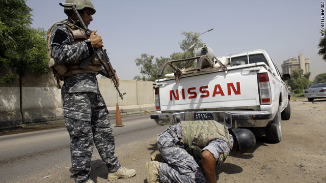 Iraqi police check a truck for explosives after a checkpoint in Baghdad was attacked on Tuesday.