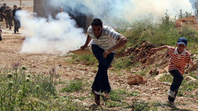 A Palestinian man and a boy run from Israeli soldiers during protests in the West Bank village of Nilin in March 2010.