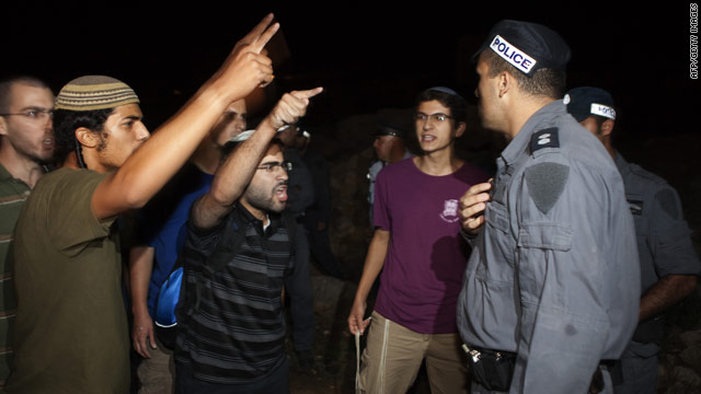 Israeli settlers express anger in front of Israeli policemen after a settler's car was ambushed by gunmen.