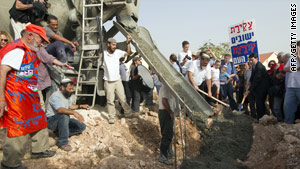 Israeli settlers surround a cement mixer as it pours cement into a new house in a West Bank settlement on Sunday.