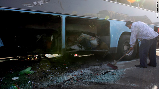 A worker clears shattered glass from the scene of a bombing that targeted a bus of Iranian pilgrims Tuesday in Baghdad.