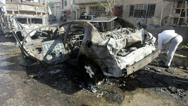 A man checks out the charred remains of a vehicle targeted in a bombing Monday in Najaf, Iraq.