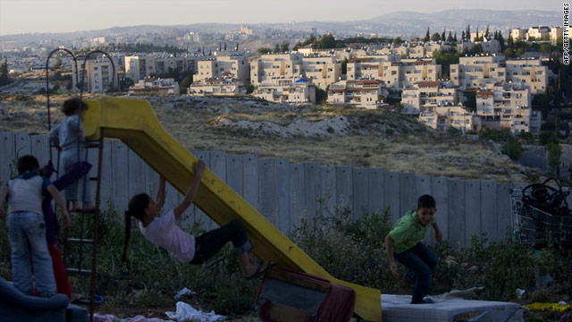 Palestinian children play on one side of a barrier wall.