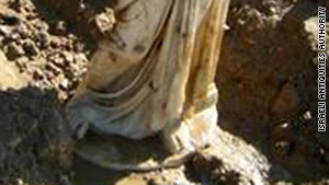 The white marble statue of a woman wearing a toga and sandals has no head or arms.