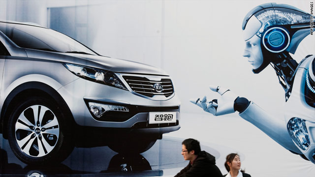 A Chinese woman rides on the back of bicycle past a billboard outside the venue of the Shanghai Auto Show show on April 14.