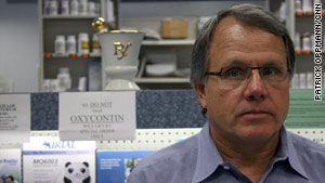 Pharmacist Bill McNary stands in front of a sign telling would-be robbers that he has no OxyContin in stock.
