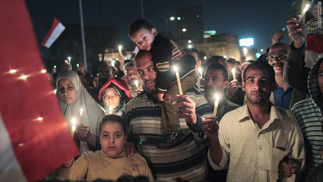 Anti-government protesters walk in Tahrir Square during a candlelight vigil for those killed during the uprising.