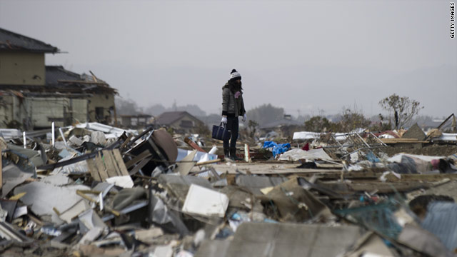 A woman stands on debris in Natori, Miyagi Prefecture, after the 9.0 earthquake and tsunami in Japan.