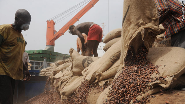 Ivorian workers empty bags of cocoa beans into a container at the Port of Abidjan.