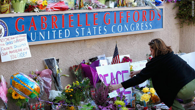 A woman places a sign at a tribute to Rep. Gabrielle Giffords outside Giffords' office in Tucson, Arizona, on Sunday.