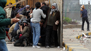 Foreign journalists and Egyptian anti-government protesters take cover behind makeshift shields in Cairo.