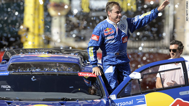 Spain's driver Carlos Sainz waves from his Volkswagen on the podium during the start of the Dakar 2011 Rally.