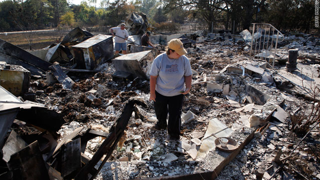 Hillary Polly looks through the rubble of her family's burned house on Wednesday near Bastrop, Texas.