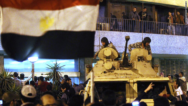 Egyptian protesters gather around the national television building as members of the presidential guard stand by Friday in Cairo.