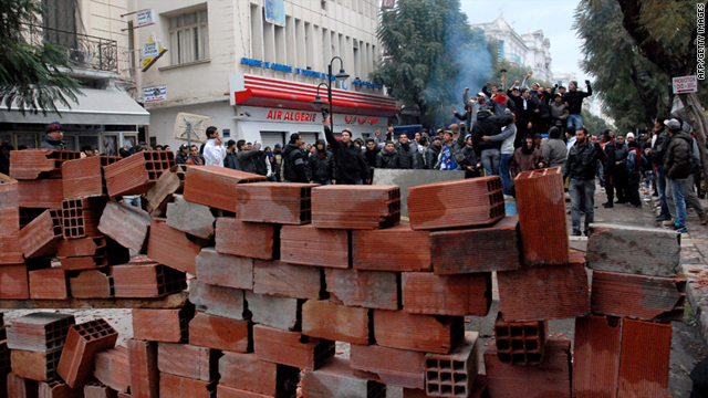 Tunisian demonstrators stand behind a barricade as they clash with Tunisian security forces during an anti-government protest in Tunis on February 26, 2011.