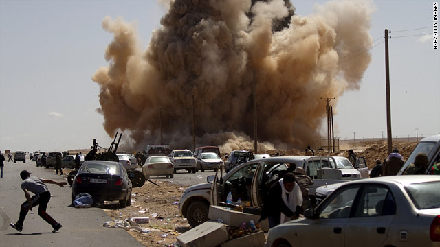 Rebel fighters take cover as a bomb dropped by a fighter jet explodes on the outskirts of Ras Lanuf on March 7.