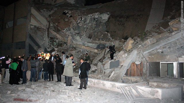People stand near the rubble after a missile destroyed an administrative building of Moammar Gadhafi's residence in Tripoli on Sunday.