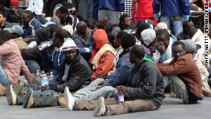 Refugees from Libya wait after disembarking from a boat onto the Italian island of Lampedusa on April 19, 2011.