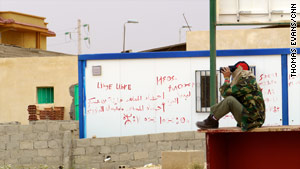 Near the Libya-Tunisia border, a rebel spotter watches rockets strike a few kilometers from the vital crossing.