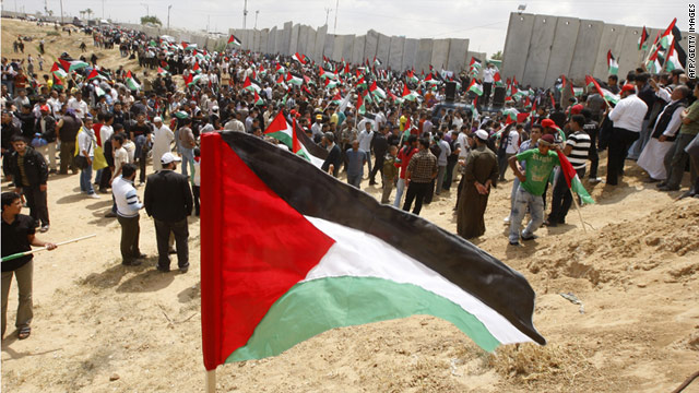 Palestinians hold up their flag as they rally along the Rafah border.