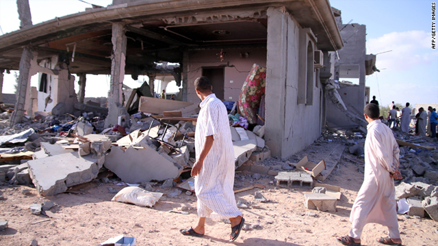 People walk past destroyed buildings on Monday, in Majer, south of Zliten.