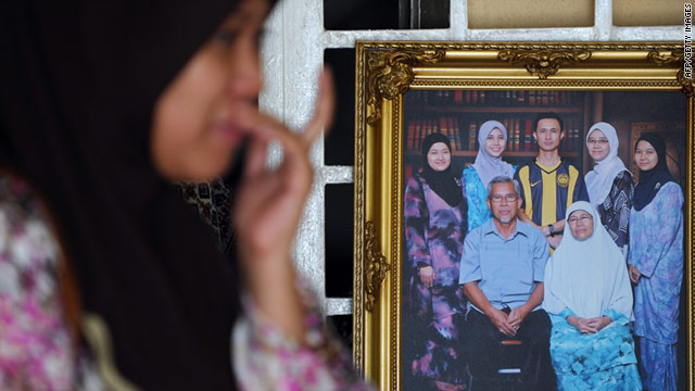 A relative of Bernama TV journalist Noramfaizul Mohd Nor mourns next to a group family photo showing the cameraman.