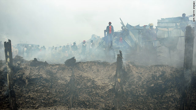 Residents of the Nairobi slum stand among smouldering debris following the fierce fire.