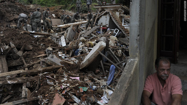 A resident sits at home as rescue workers rummage through the scene of a landslide in Nova Friburgo, Brazil, on Tuesday.