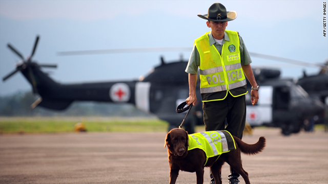 A Colombian police officer with a police dog stands guard next to two Brazilian helicopters with the Red Cross colors at the airport of Florencia, department of Caqueta, Colombia, on Thursday.