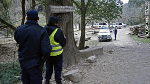 Police officers on Saturday stand at the entrance to a hiking trail where two French tourists were killed in Salta, Argentina.