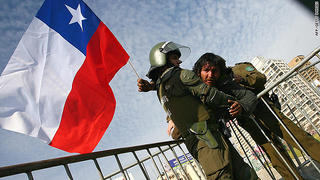 A Chilean protestor waving the national flag is confronted by police.  (Photo Courtesy of CNN)