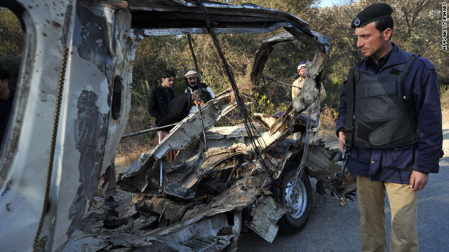 A Pakistani policeman stands near the wreckage of a passenger van after a bomb blast in Jawarza, near Hangu.