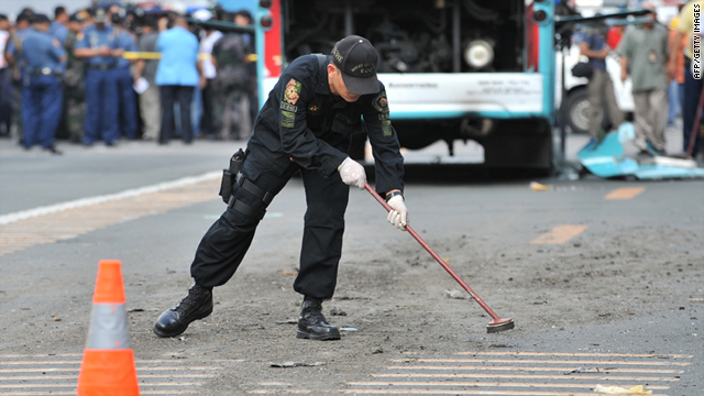 A Philippine police investigator looks for evidence next to a bus where a bomb exploded inside along the main avenue in the financial district of Manila on Tuesday.