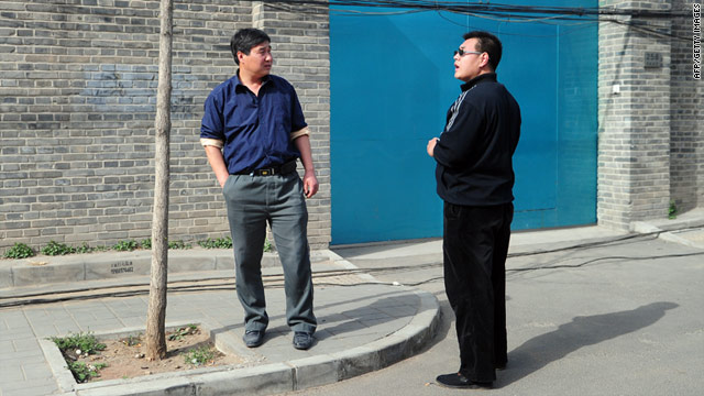 A plainclothes policeman (R) stands in front of the entrance to the studio of outspoken artist Ai Weiwei in Beijing on April 8, 2011.