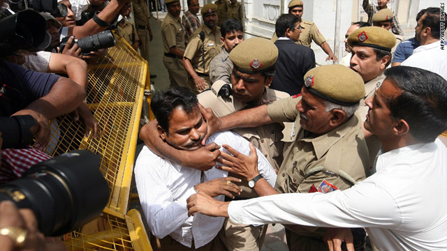 An unidentified man (L) was arrested after throwing a shoe at Suresh Kalmadi as he was escorted into a New Delhi court Tuesday.