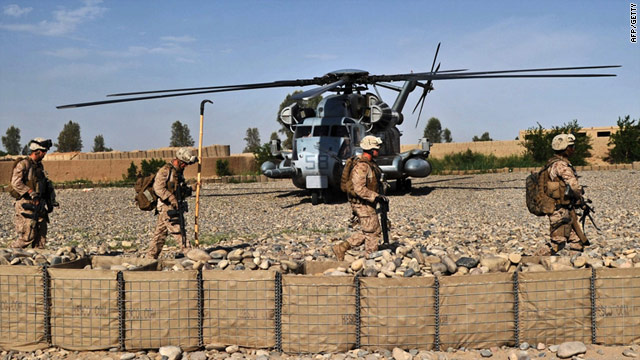 U.S. Marines walk past a Marine helicopter after an early morning operation in Helmand Province on Monday.