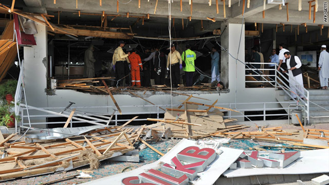 Pakistani security officials examine a damaged Islamabad bank, where a suicide bombing killed a bank guard on Monday.