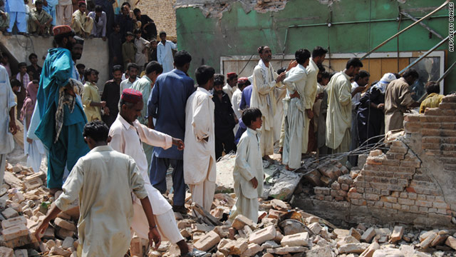 Pakistanis walk through a restaurant destroyed by a bomb in the town of Dera Allah Yar on Sunday.