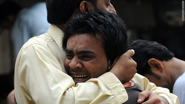 A Pakistani man comforts a mourner after dozens of people were killed in Karachi after a fresh spate of violence on August 18.