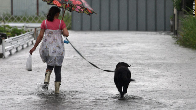 A woman walks with her dog through floodwaters caused by Typhoon Talas at Higashiyama, Japan on September 3, 2011.