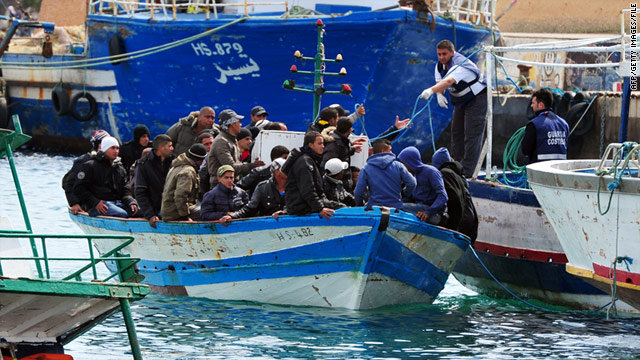 Immigrants in a boat are helped as they arrive in Lampedusa harbor off the southern Italian island on March 30, 2011.