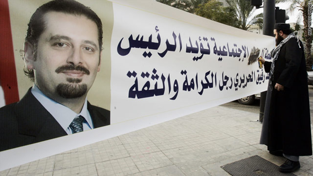 A Sunni Muslim cleric from the pro-Hezbollah Islamic Labour Front sprays his family's name on a banner supporting Lebanon's caretaker prime minister Saad Hariri (portrait) in Sidon on January 18.